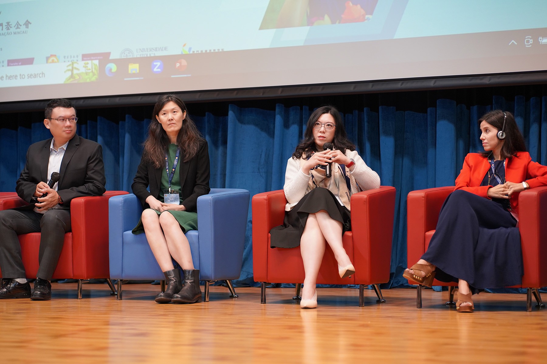 Dr Elsa speaking into a microphone while seated on a conference panel